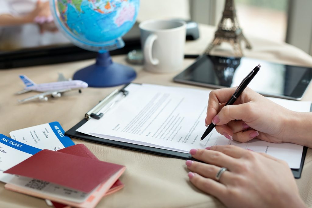 A female travel agent in the office signs a contract, close-up