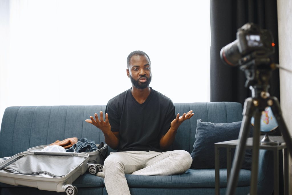 African male blogger recording vlog on digital camera