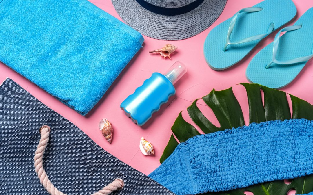 Beach essentials and blue beach bag on pink background