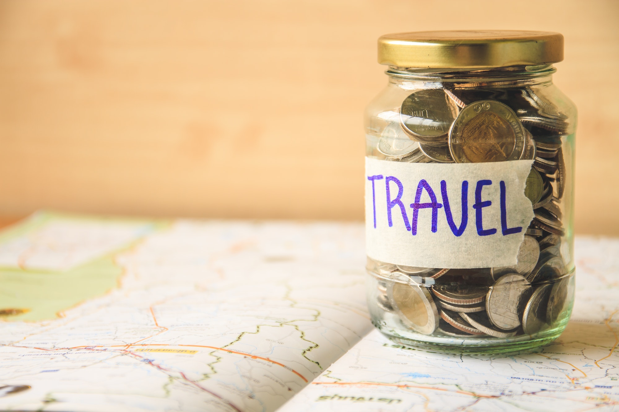 Coins in a glass jar on a map. Saving money for travel concept
