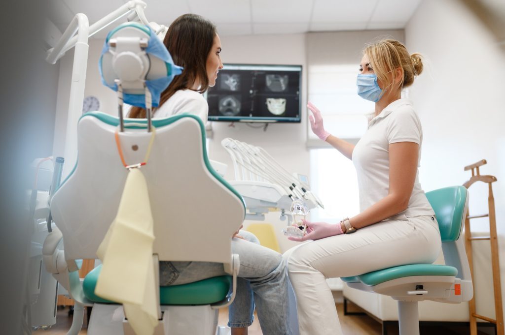 Female dentist shows to patient x-ray of teeth