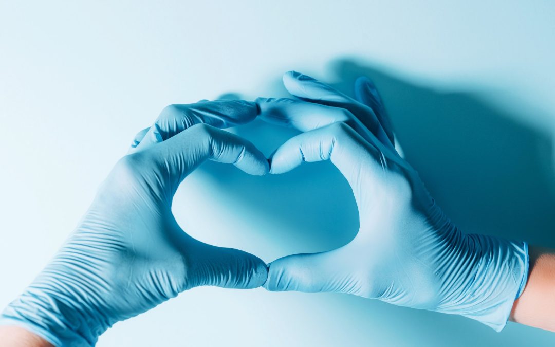Figure heart built with hands in medical gloves on blue background. Copy space. National Doctors'