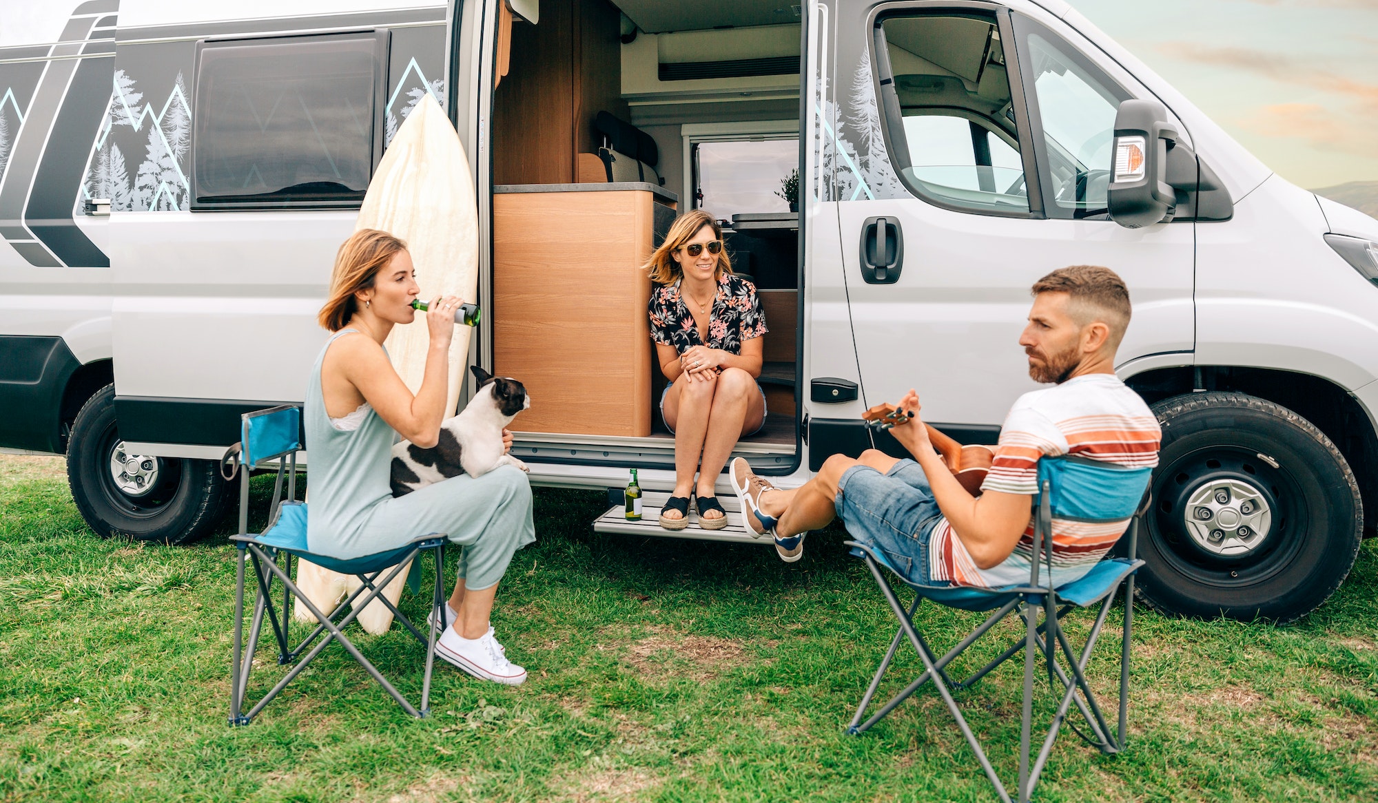 Friends with their dog drinking beer in front of their camper van