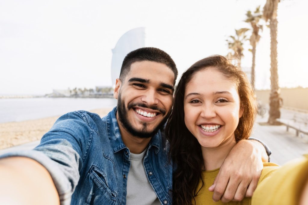 Happy couple having fun doing selfie in barcelona city - Focus on faces