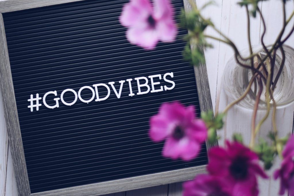 Hashtag GOOD VIBES on a letter board with a bouquet of pink anemone flowers