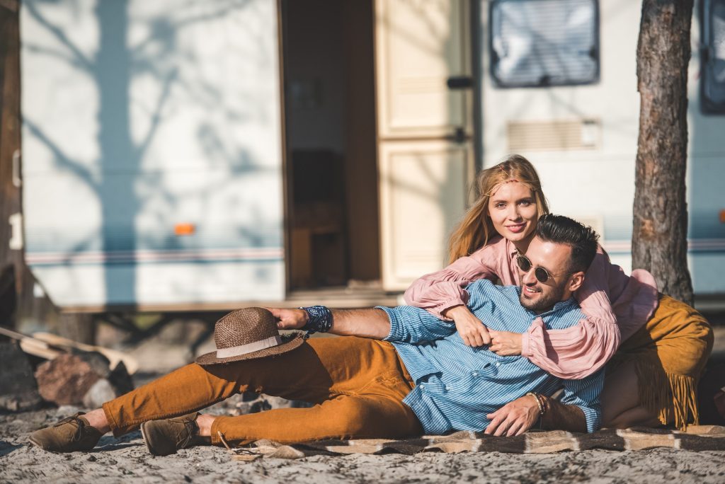 hippie couple lying on blanket near camper van