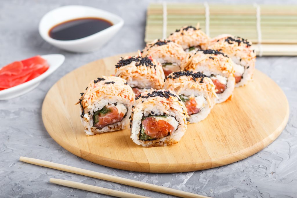 Japanese maki sushi rolls with salmon, sesame, chopsticks, soy sauce and marinated ginger