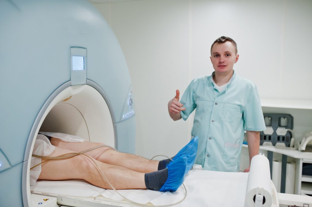 Male doctor turns on magnetic resonance imaging machine with patient inside.