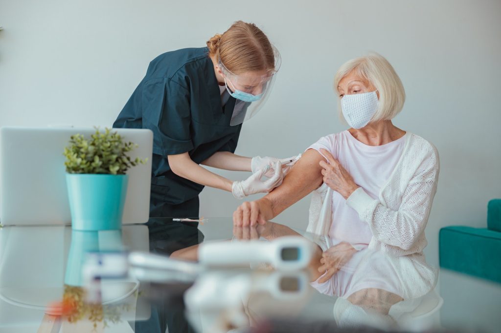 nurse-giving-injection-to-senior-woman-in-living-room-1024x682-7971816