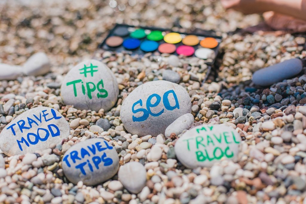 On the beach are stones painted watercolors with different words and phrases. Inscriptions on stones