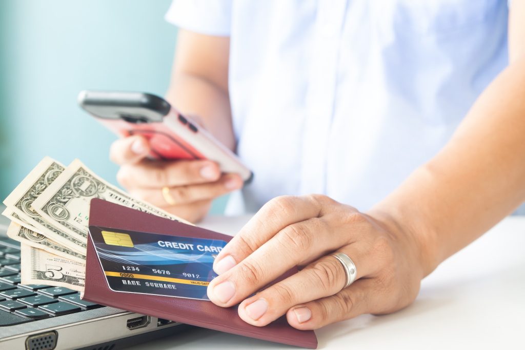 Online payment, Man's hands holding a credit card, passport and money. Using mobile phone