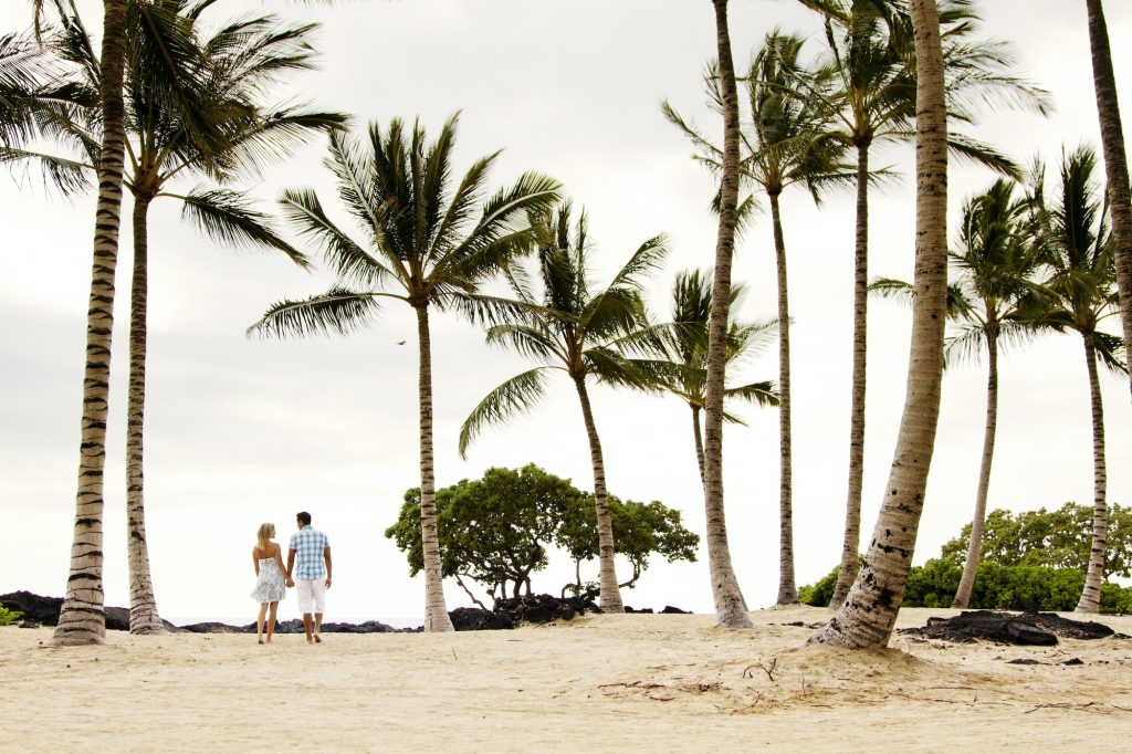 Rear View Of Couple Walking On Sand At Beach