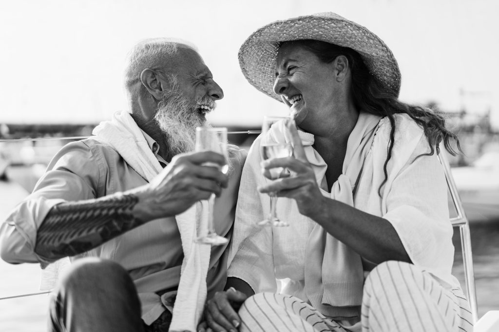 Senior couple cheering with champagne on boat during summer vacation