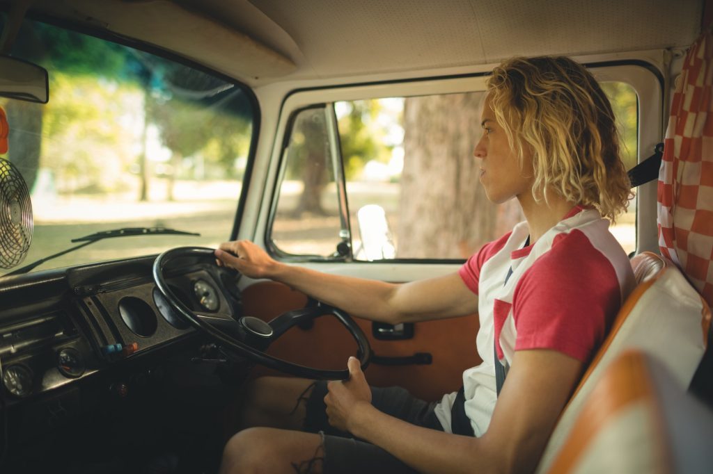 Side view of young man driving camper van