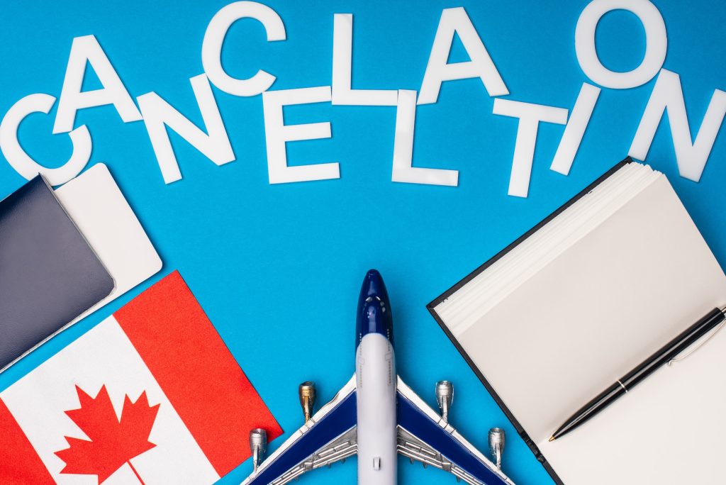 Top view of toy plane, cancellation lettering near flag of canada and passport with air ticket on
