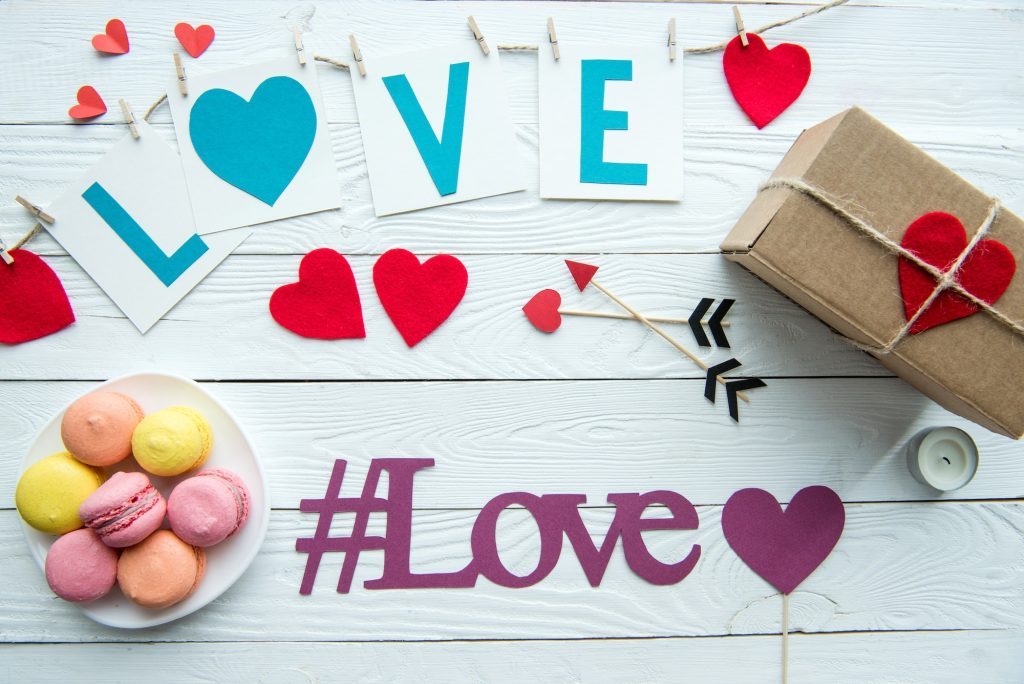 top-view-of-valentines-day-decorations-macaroon-cookies-gift-box-and-love-hashtag-sign-on-wooden-1024x684-3995656
