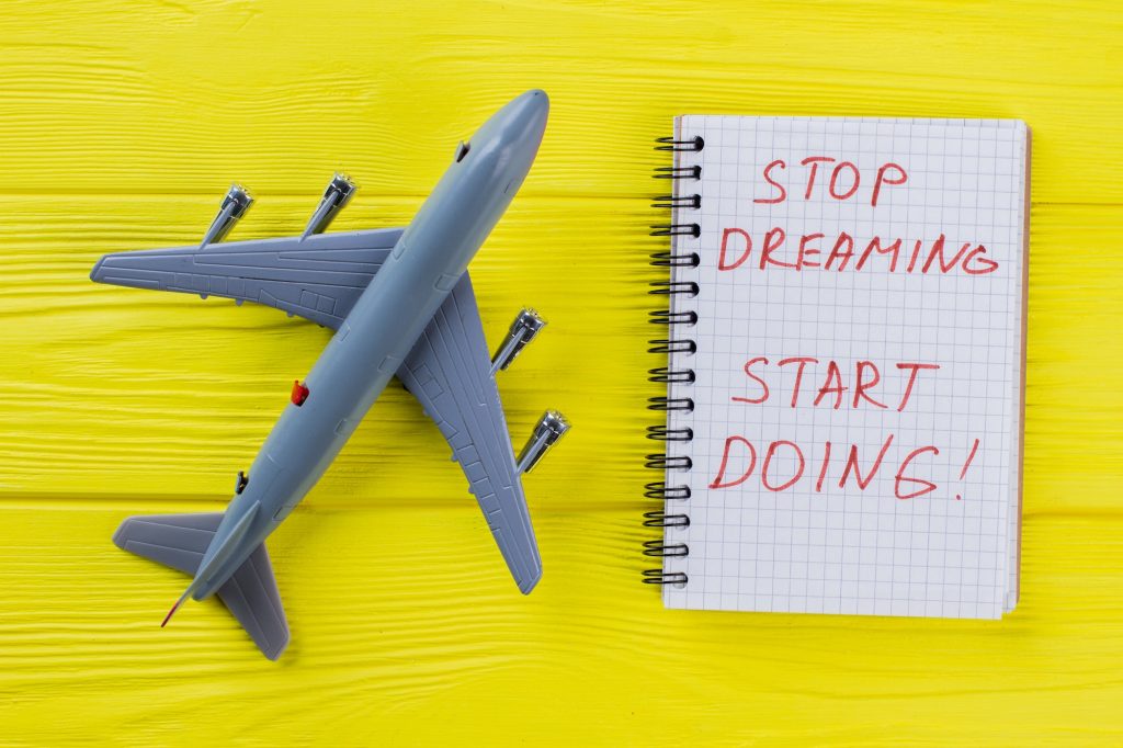 Toy passanger airplane and notepad with motivation quote.