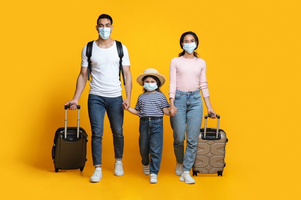 Travel During Pandemic. Arab Tourists Family Wearing Protective Masks Walking With Suitcases