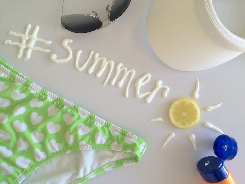 Travel. Flat lay of summer essentials with the hashtag #summer word made with sunscreen & lemon sun