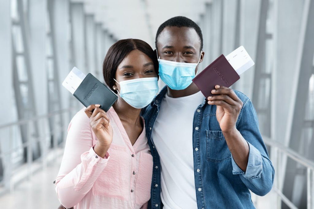 Travel Safe. Black couple in medical masks posing with passports at airport