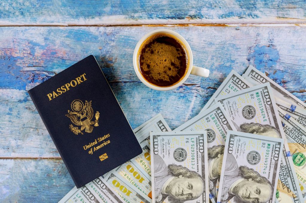 US passport with dollar bill and cup of coffee on blue wooden table.