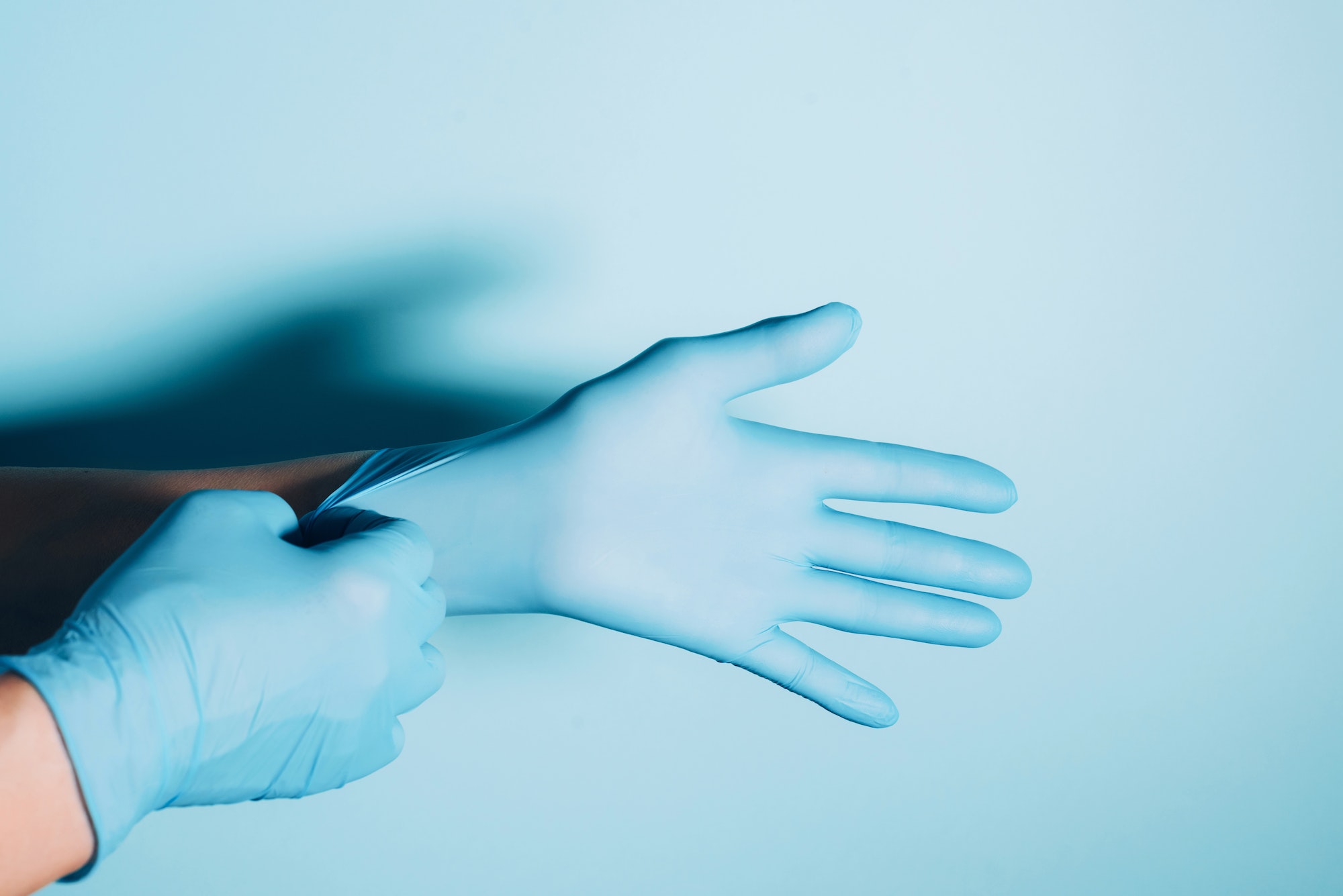 Woman doctor wears medical gloves over blue background. Copy space. National Doctors' Day