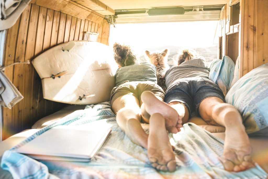 Young couple with dog traveling with dog on vintage minivan