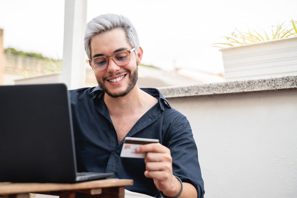 young-hipster-man-holding-credit-cart-using-computer-laptop-for-online-payment-e-commerce-bank-1024x684-9228533