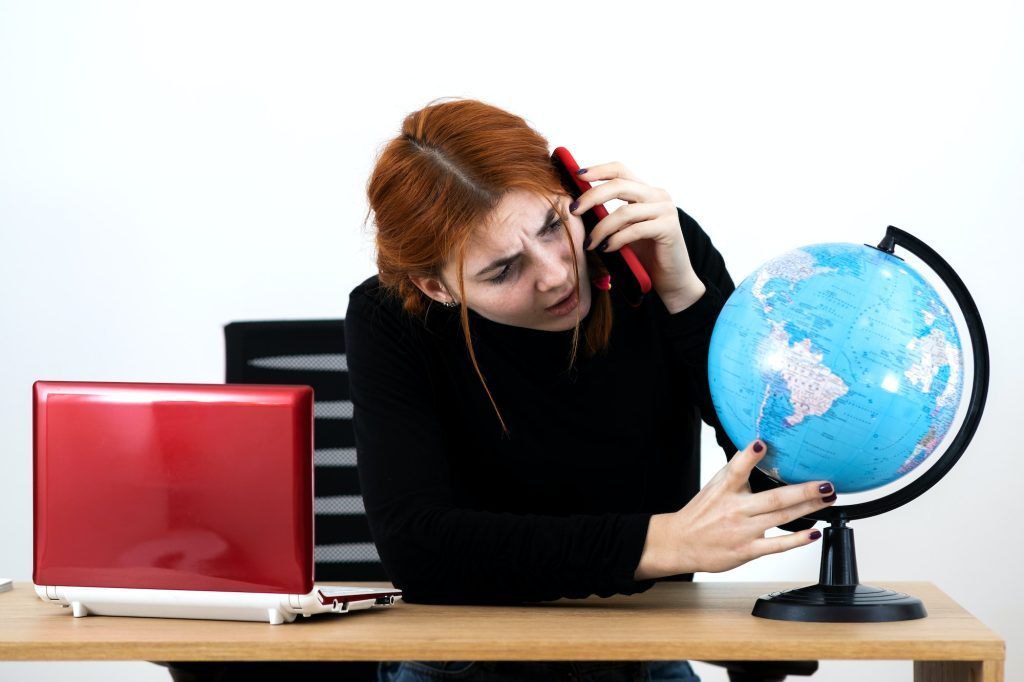 Young travel agent woman sitting behind working desk with laptop computer