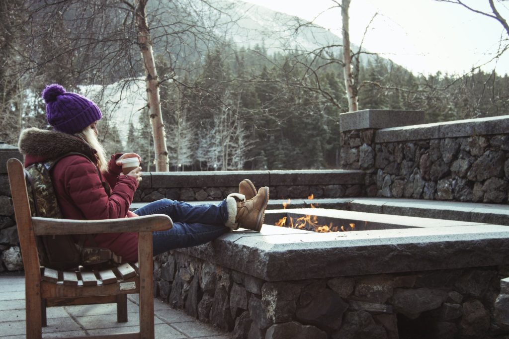 Young woman sitting on bench with fire pit, Girdwood, Anchorage, Alaska
